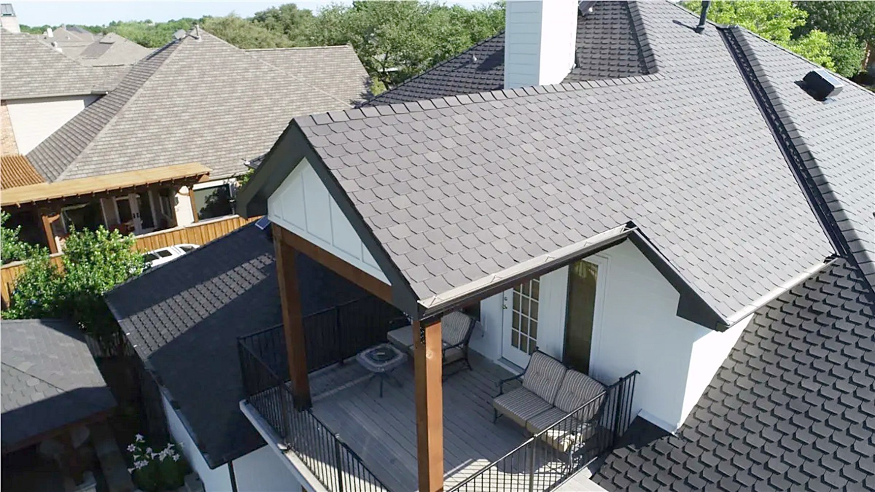 Aerial view of a new gray shingle roof over a home with a covered back patio
