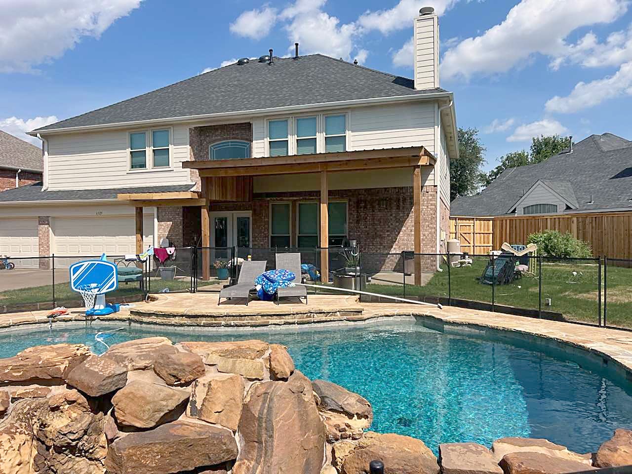 A two-story home with a covered patio and a rock-edged pool in the back yard